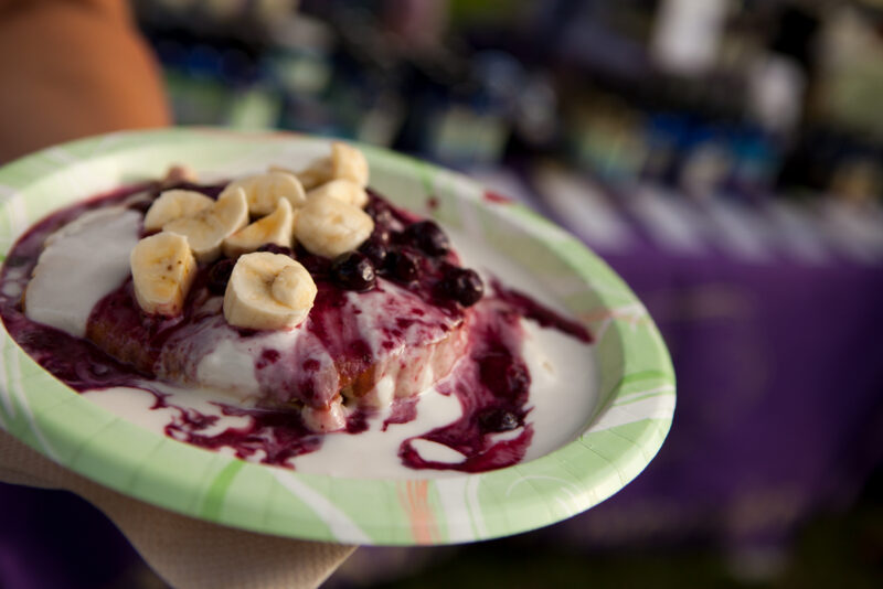 Bananas and berry sauce on a paper plate.