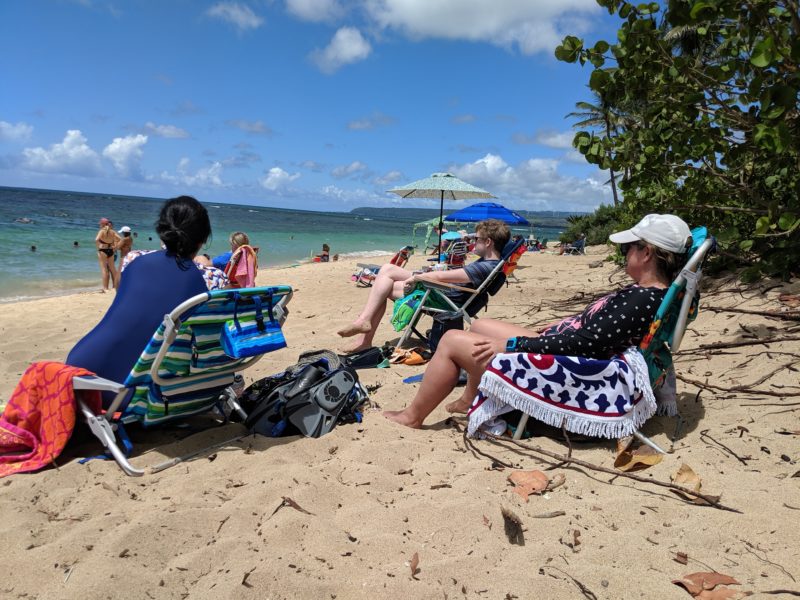 People sitting on beach chairs on sand.