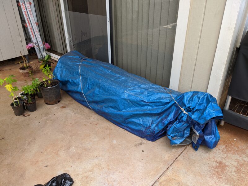 Wrapping loose wood and pipe in a tarp and securing them in a sheltered corner outside.