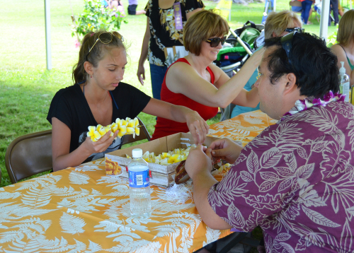 Learning how to make a lei for the first time at the Lei Day celebration. Editorial credit: Andmir / Shutterstock.com