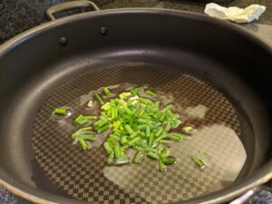 Add green onions to the hot oil and cook for several seconds.