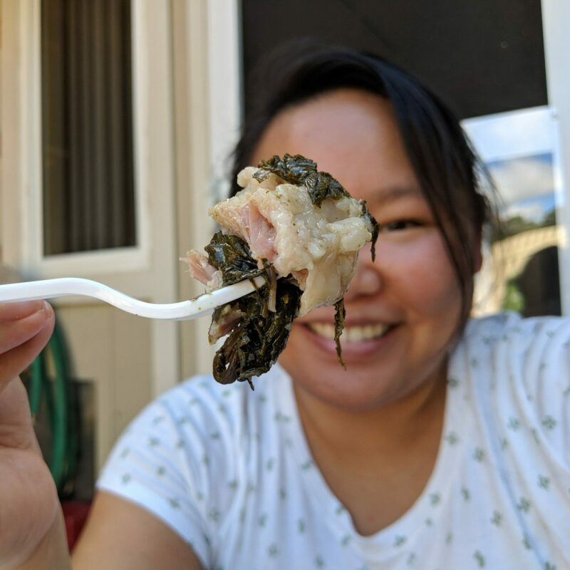 Amy eating a forkful of laulau from the side of the road.