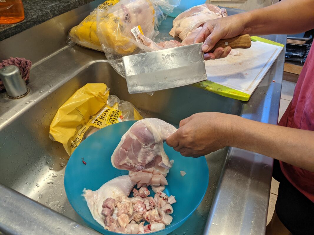 Cutting chicken with a butcher's knife.
