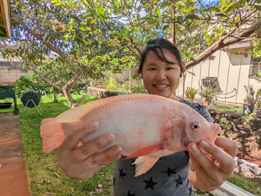 Amy holding up a tilapia fish.
