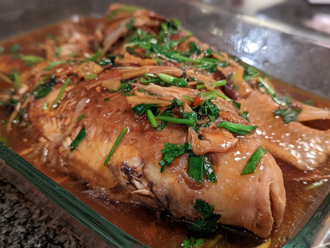 Tilapia cooked and seasoned with ginger and green onions.