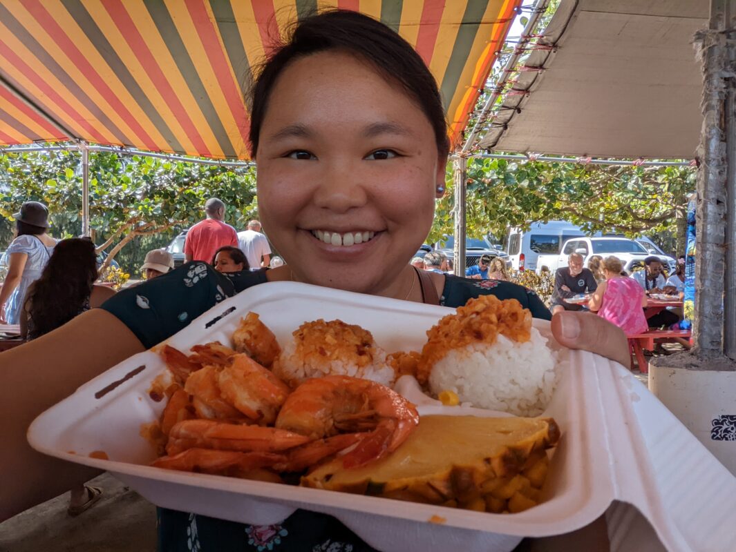 Amy holding a shrimp plate lunch and smiling.