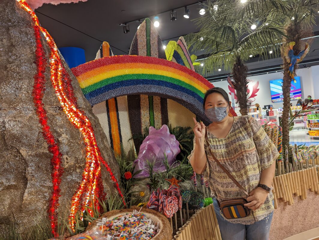 Amy standing in front of a candied rainbow and volcano.