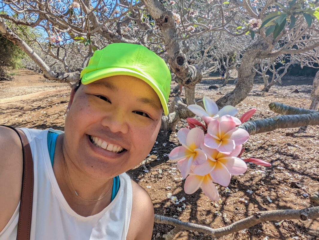 Amy smiling next to some blossoming plumerias.