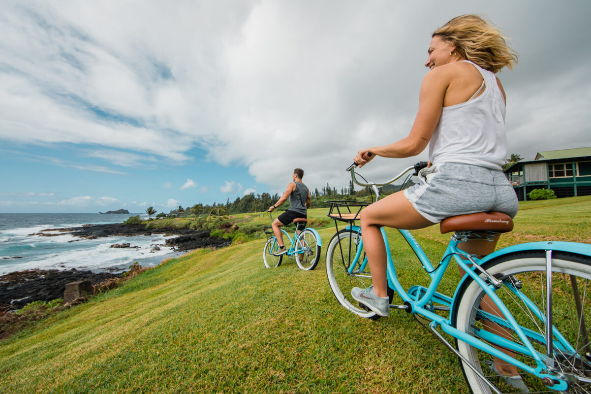 Couple riding bicycles on grass.