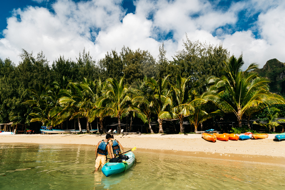 Couple walking kayak to a beach.