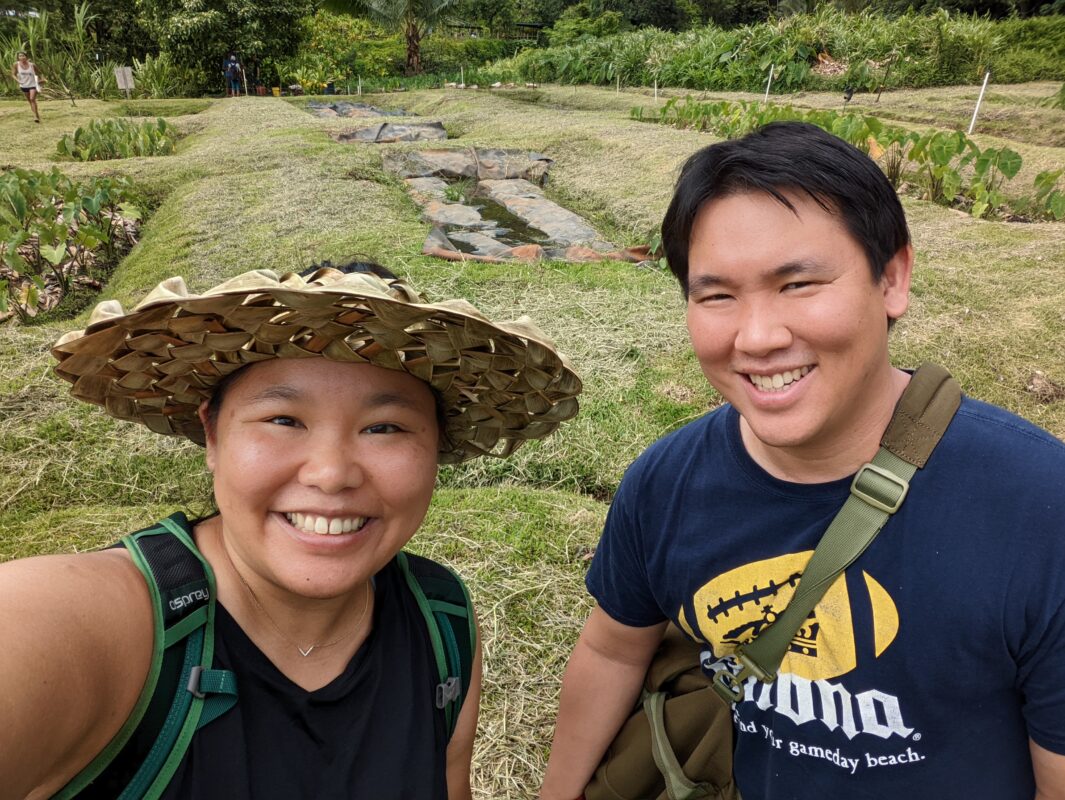 A man and woman smiling into the camera on farmland.