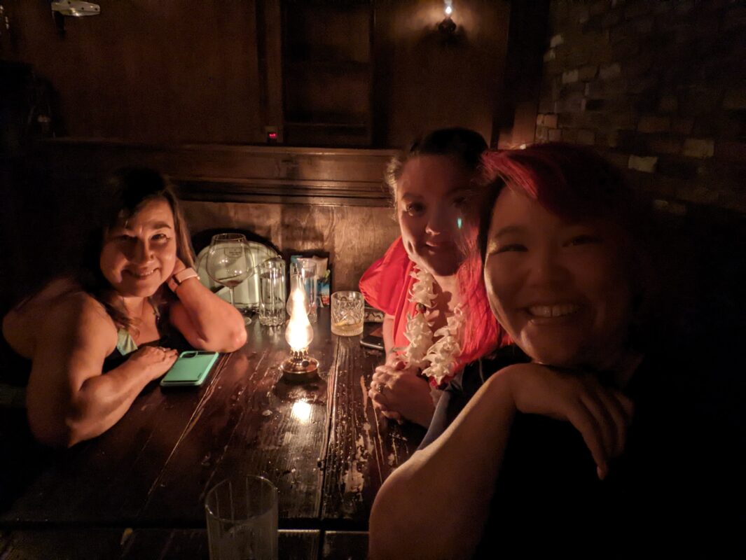 3 women sitting in a candlelit restaurant.